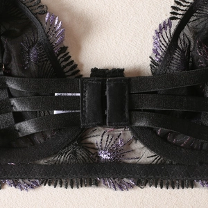 Detailed back view of black lace bra featuring purple floral embroidery and triple hook closure