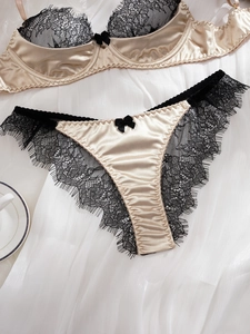 Detailaufnahme von Champagner-Satin-Dessous-Set mit schwarzer Spitze und Schleife