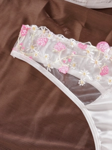 Gros plan détaillé de lingerie en satin blanc avec broderie florale en dentelle