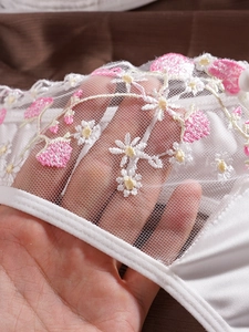 Gros plan détaillé montrant la dentelle en maille blanche et la broderie florale
