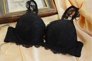 Detailed close-up of black floral lace bra with intricate patterns and metallic pendant
