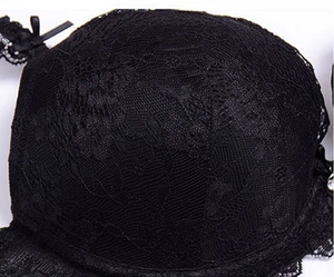 Detailed close-up of floral black lace bra cup with delicate bow and rhinestone charm