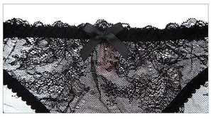 Detailed macro view of black floral lace fabric with a delicate silk satin bow