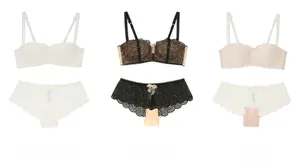 Détail à plat des ensembles soutien-gorge et culotte en dentelle florale blanc, noir et rose