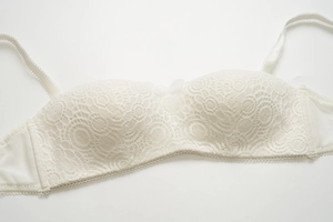 Détail d'une brassière en dentelle blanche avec nœud et bretelles amovibles
