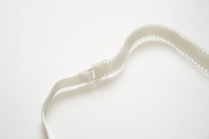 Détail d'une bretelle de lingerie blanche avec anneau en plastique et bordure dentelle