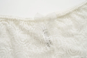 Détail de sous-vêtement en dentelle blanche avec nœud et étiquette de taille M/L/XL
