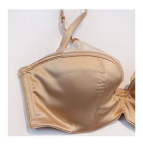 Détail du soutien-gorge en satin champagne avec bordure en dentelle blanche délicate