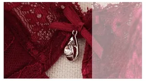 Détail du soutien-gorge en dentelle bordeaux avec nœud en satin et pendentif strass brillant