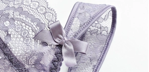 Dettaglio macro di lingerie in pizzo floreale lilla con un fiocco di raso fine