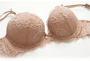 Dettaglio del reggiseno in pizzo beige con ricami floreali e un piccolo fiocco centrale
