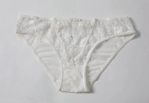 Détail de culotte en dentelle blanche avec broderie florale en V et petit nœud central