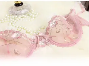 Dettaglio del reggiseno in pizzo rosa con ricamo floreale e accenti di piccole perle