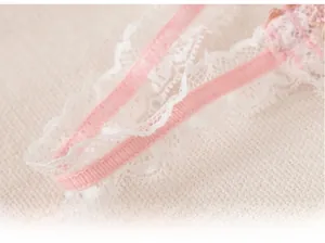 Dettaglio delle spalline rosa del reggiseno con delicato bordo in pizzo bianco ricamato