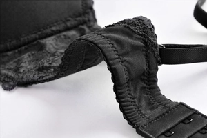 Macro detail of black lace lingerie side wings with smooth fabric and hook closure