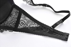 Detail of black lace bra with adjustable straps and rear hook closure on white background