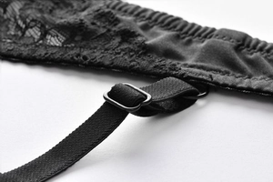 Detail of black floral lace and adjustable satin strap with metal buckle on bra