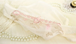 Dettaglio del reggiseno in pizzo avorio con ricamo floreale rosa e fiocco di raso fine