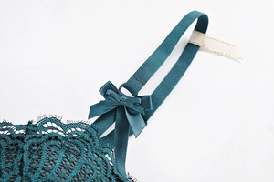 Detail of dark green eyelash lace bodysuit showing silk bow and adjustable strap