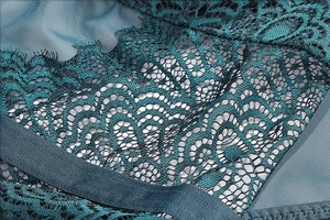 Macro shot of dark teal floral lace and breathable mesh fabric on a slimming bodysuit