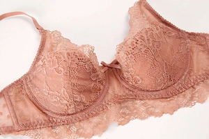 Macro detail of nude pink floral lace bra with elegant embroidery and silk ribbon bow