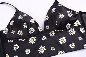 Detail of black satin bralette featuring white daisy prints and smooth silky texture