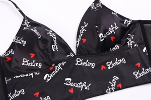Detailed close-up of black satin bra with heart prints and sheer mesh side panels