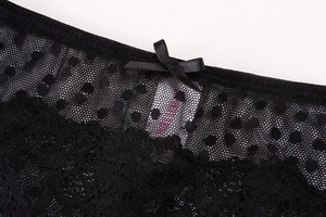Close-up of black lace bra detail with mesh polka dots and a small satin bow embellishment