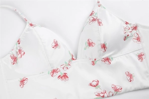 Close-up detail of smooth satin fabric with pink floral print and delicate thin straps