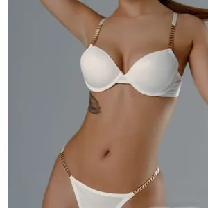 Détail d'un ensemble de lingerie en satin blanc avec chaînes dorées élégantes