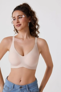 Vue de face du soutien-gorge beige sans couture ni armature porté avec un jean bleu