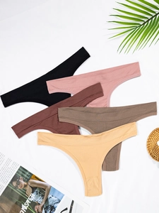 Flat lay of five seamless thong panties in neutral colors with soft fabric detail