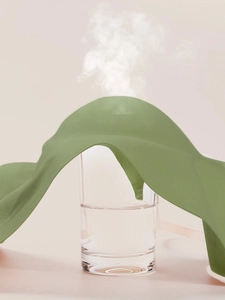 Green wavy silicone steam eye mask accessory used over a hot water glass with rising steam