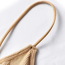 Detailed macro view of the thin shoulder strap seam on a ribbed sand beige padded bralette