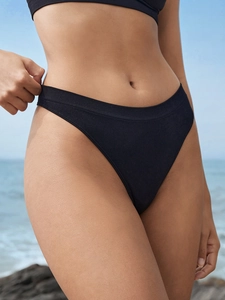 Gros plan d'un string sans couture en soie glacée noire avec texture côtelée sur la plage