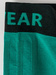 Detail of elastic knit waistband with green EAR lettering on black ribbed fabric