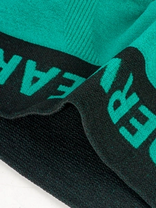 Close-up of knit fabric texture with green logo on black elastic waistband detail