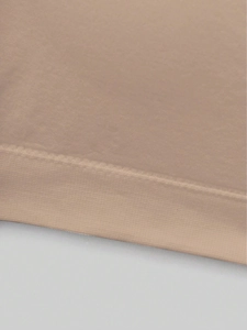 Detailed macro view of the seamless knit fabric and reinforced edges on the skin-tone tube top