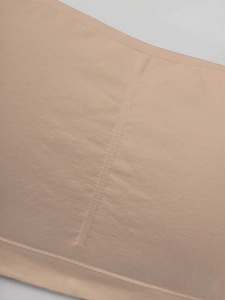 Close-up of nude seamless fabric with reinforced side stitching for girls' tube top