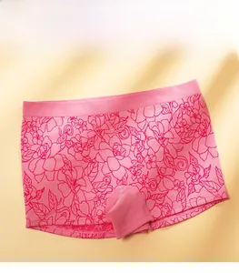 Flat lay of pink seamless boxer briefs with red floral patterns on a warm background