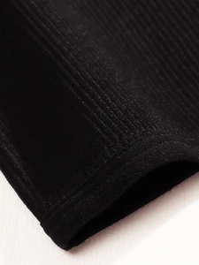Détail macro du tissu en maille côtelée noire montrant coutures et texture