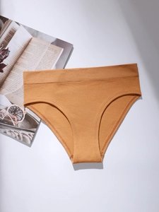 Detail of ginger yellow seamless panty with elastic ribbed waistband on flat surface