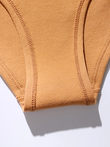 Detailed macro view of the ginger yellow ribbed fabric and reinforced seamless stitching