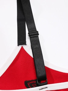 Detail of red sports bra with white trim and adjustable black elastic shoulder straps