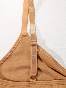 Detail of adjustable shoulder strap on tan sports bra with rose gold metal buckle
