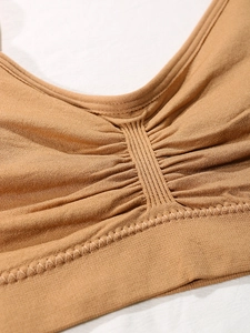 Detail of caramel seamless ribbed sports bra with center cinched detail and wide hem