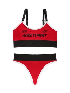 Flat lay of red and black seamless sports bra set with achievement text branding