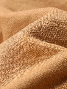 Macro shot of breathable camel knit fabric showing fine texture and seamless weaving