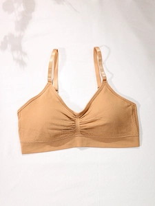 Detail of skin-colored seamless sports bra featuring deep V-neck and soft pleated center