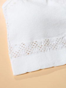 Detail of white ribbed sports bra featuring breathable geometric hollow lace hem